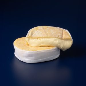 Queso DaJosefa de leche cruda de vaca presentado entero y cortado por la mitad, mostrando su interior extremadamente cremoso.
